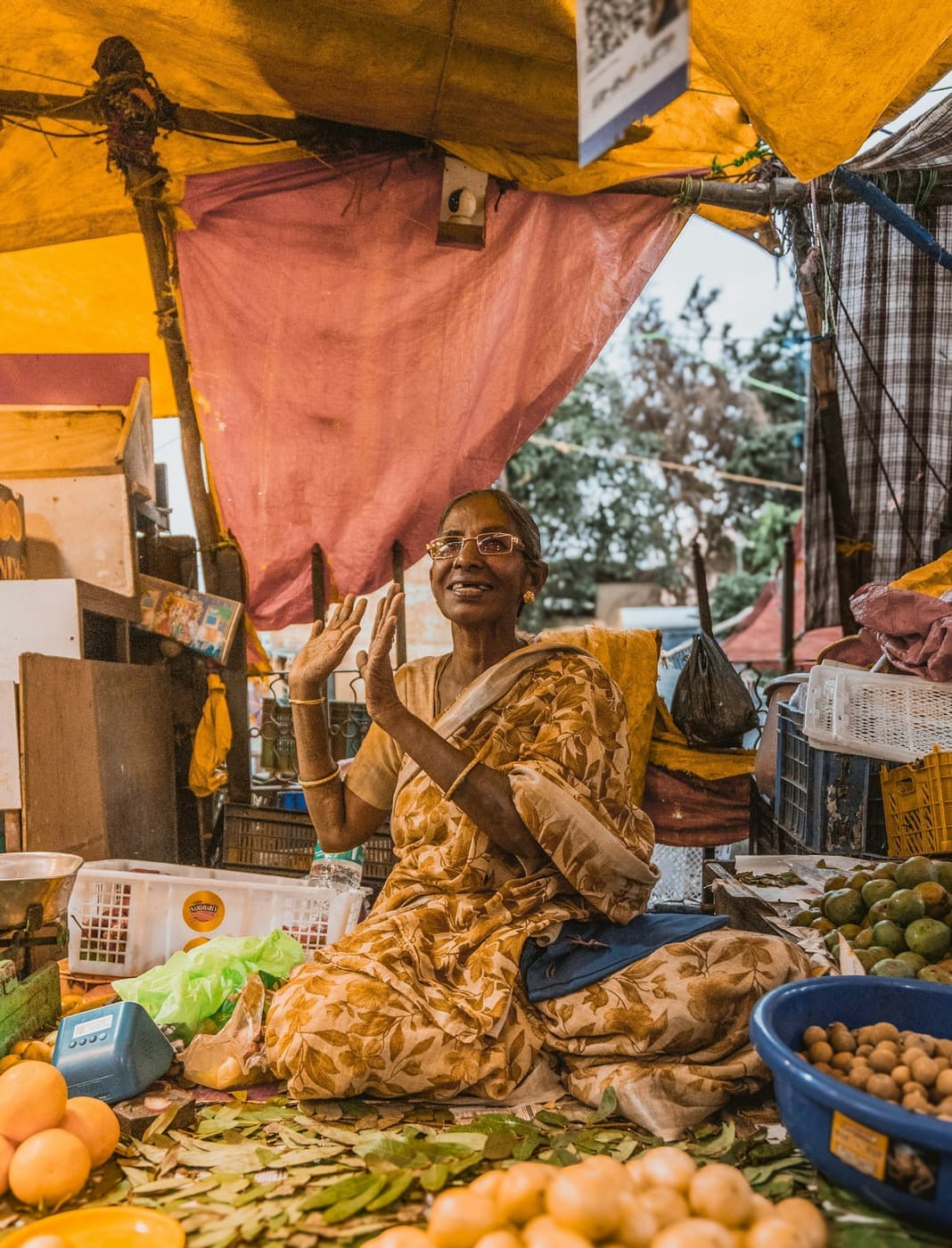 A smiling vendor at her fruit and vegetable stall