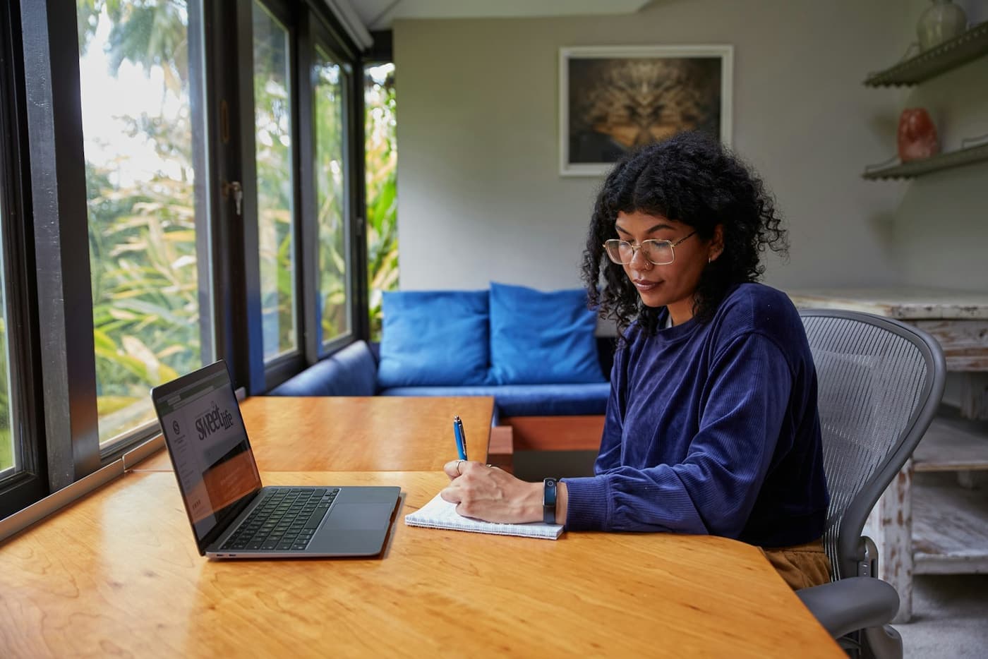 A woman working from her laptop at a desk by the window